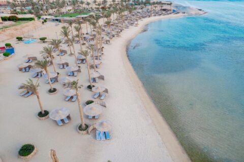 Flyfoto av stranden ved Blend Elphistone Resort, med palmer, stråparasoller og turkist hav