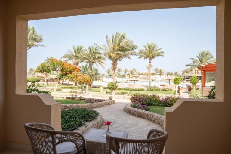 En terrasse med to flettede lenestoler, med utsikt mot de blomstrende hagene og palmene på Blend Elphistone Resort
