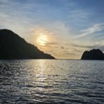 Cocos Island i motlys ved solnedgang, med en dykkesafaribåt for anker til høyre og rolig hav