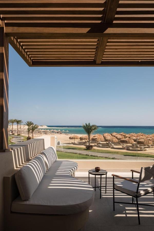 En skyggefull terrasse med lenestoler, mot stranden og havet