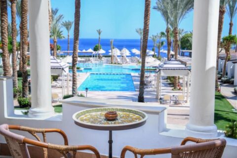 Utsikten fra en terrasse på JAZ Fanara Resort over bassengene, palmene og Rødehavet