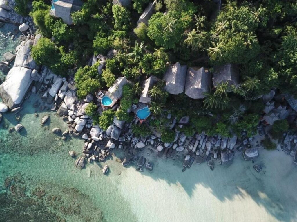 Koh Tao Cabana sett fra luften, med hyttene mellom trærne, klippene og den hvite sandstranden