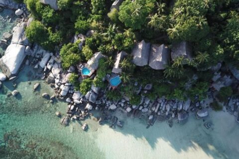 Koh Tao Cabana sett fra luften, med hyttene mellom trærne, klippene og den hvite sandstranden