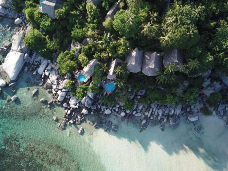 Koh Tao Cabana sett fra luften, med hyttene mellom trærne, klippene og den hvite sandstranden