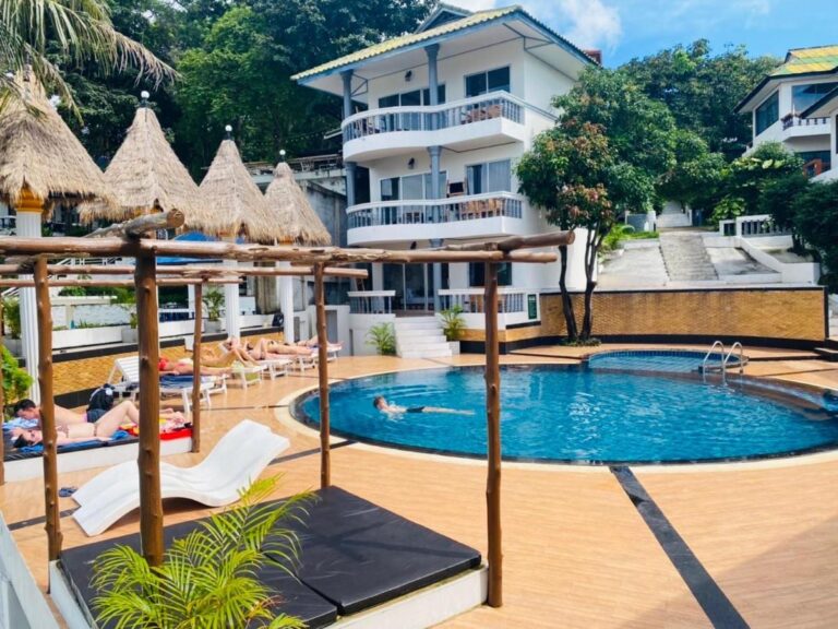 Bassenget på Koh Tao Heritage, med solsenger og stråparasoller, foran en bygning med balkonger