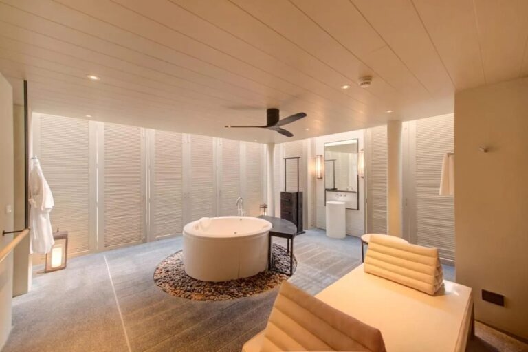 Et bad på Layana Resort med et rundt badekar på småstein og en badekåpe som henger