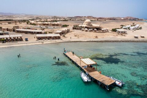 Flyfoto av Marsa Shagra Village, med brygga, to zodiacer og landsbyen ved det turkise vannet