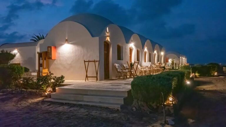 Hyttene på Marsa Shagra Village opplyst i skumringen, med terrassene sine