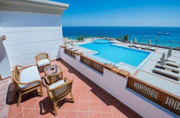 En terrasse med kurvmøbler over et stort basseng og Rødehavet, på Reef Oasis Beach Resort
