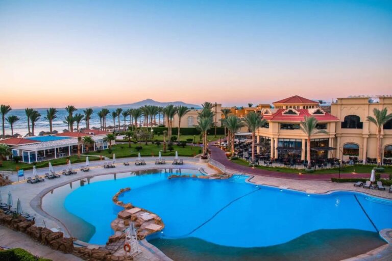 Det store bassenget på Rixos Sharm El Sheikh i solnedgang, foran palmene og Sinai-fjellene