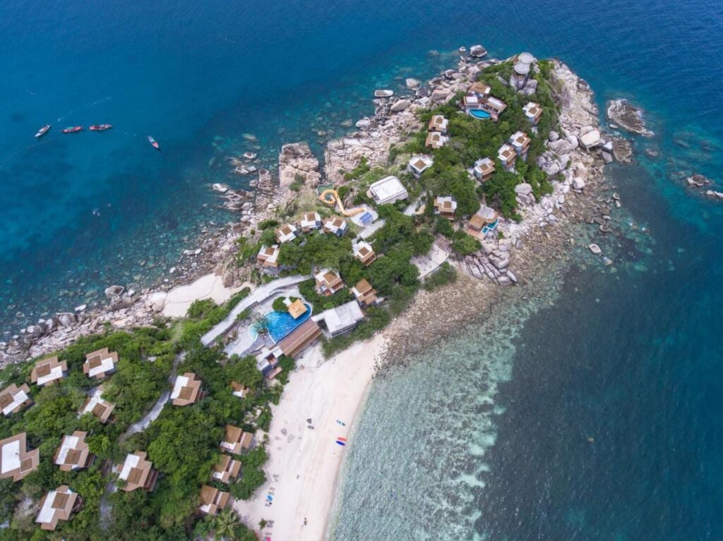 Sai Daeng Resort sett fra luften, med bungalowene på en steinete odde, bassengene og sandstranden