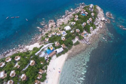 Sai Daeng Resort sett fra luften, med bungalowene på en steinete odde, bassengene og sandstranden