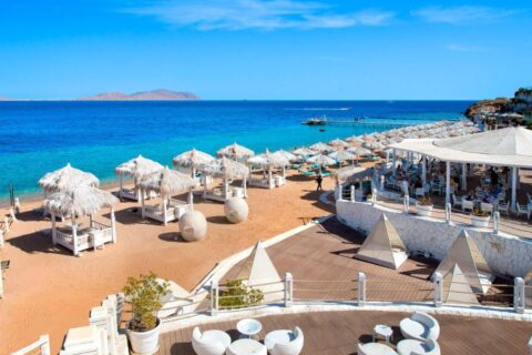 Stranden på Sunrise Arabian Beach Resort, med parasoller av strå og brygga, rett overfor Tiran-øya