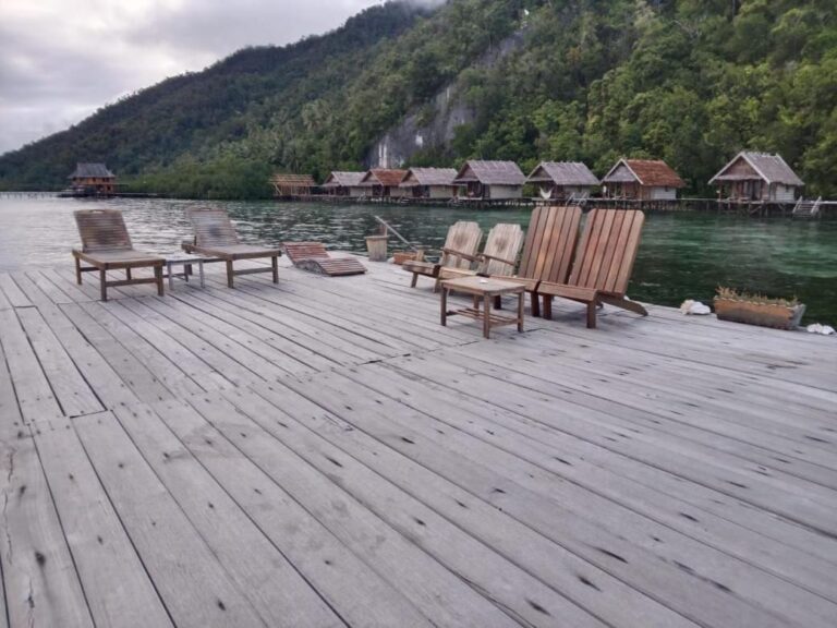 Trestoler og et lavt bord på en brygge, foran klippen og skogen