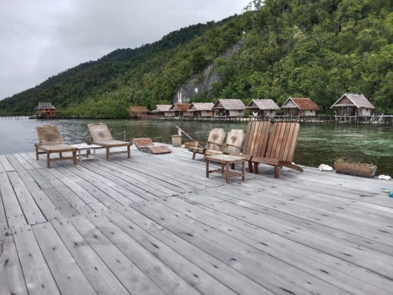 Solsenger på en brygge i grått vær, foran bungalowene og åsen