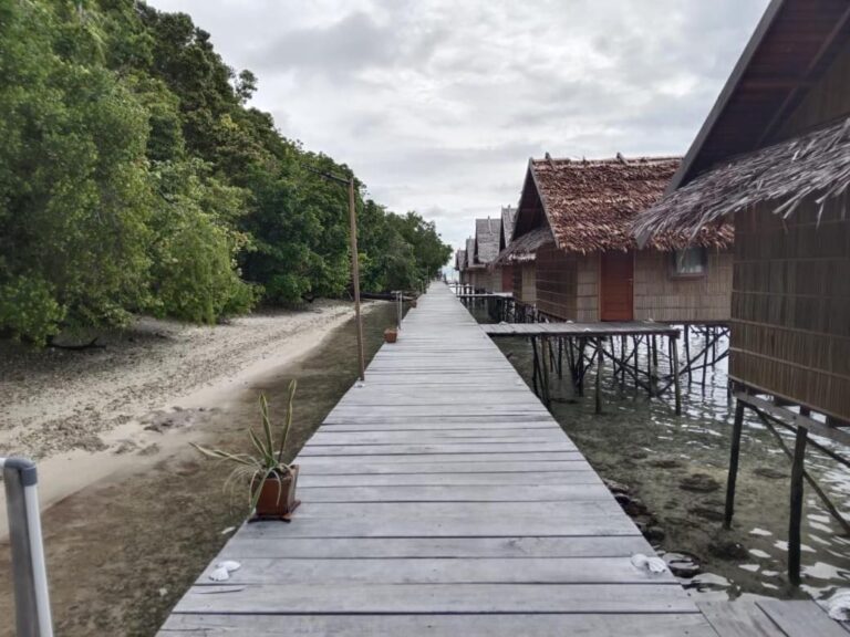 En gangbro i tre mellom stranden og bungalowene på påler